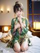 A woman in a green kimono sitting on a bed.