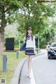 A woman in a school uniform is walking down the street.