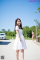 A woman in a white dress standing on a road.