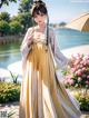 A woman in a yellow and white dress holding an umbrella.