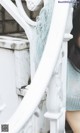 A woman in a blue dress leaning against a white railing.