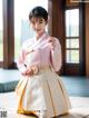 A woman in a pink and white hanbok is posing for a picture.