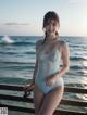 A woman in a blue bathing suit standing on a pier by the ocean.