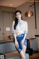 A woman in a white shirt and blue skirt posing for a picture.