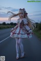 A woman with long blonde hair standing on the side of a road.