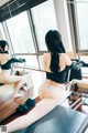 A woman in a black top and white panties sitting on a reformer.