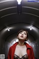 A woman in a red jacket is standing in a tunnel.